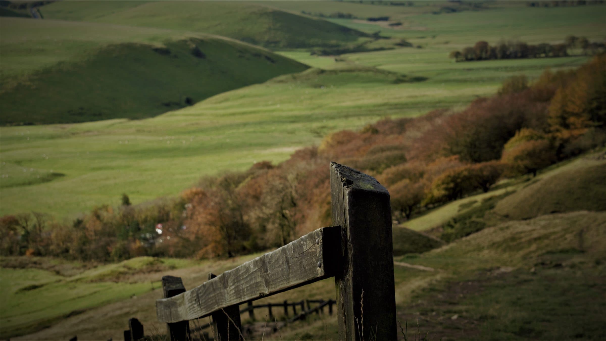 A weathered wooden gatepost in sharp focus, the Hope Valley falling away behind